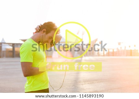 Male runner using mobile phone choose music in playlist before start workout training, young sportsman listening songs in earphones standing on street in early morning. Infographics media player sign