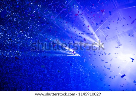 Stage lights and falling confetti at a music festival. 
