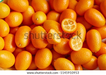 Top view of bunch of fresh kumquats in the organic food market. Some kumquats is cutted Royalty-Free Stock Photo #1145910953