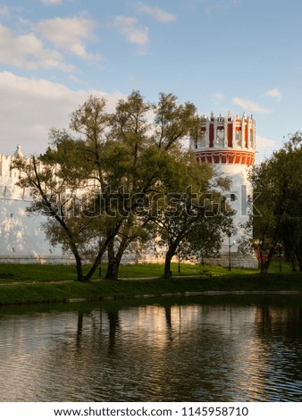 The walls and towers of the Novodevichy monastery in Moscow are reflected in the water in the summer evening before sunset