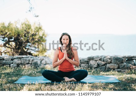 Woman practicing yoga in park by the sea