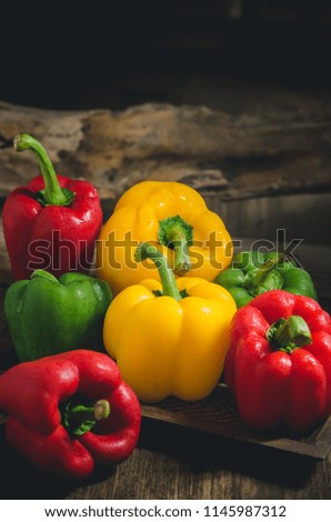 Three sweet peppers on a wooden table background.