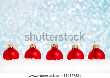 Border of Christmas tree decorations in snow against lights background