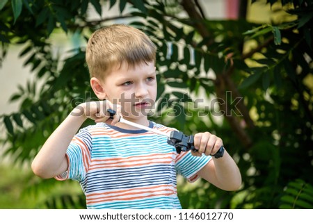 Boy playing with modern spin top outdoors. Entertainment game for children. Top, triggered by a trigger. Kid demonstrate two different variants choosing which is better.