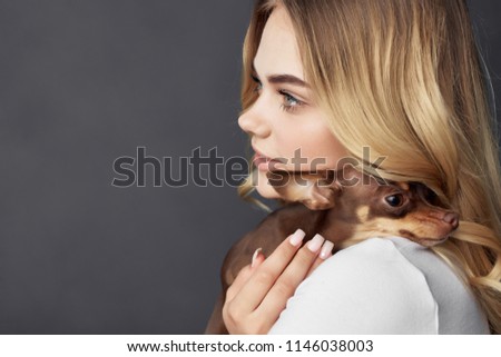   a woman in profile holds a dog on her shoulder                             