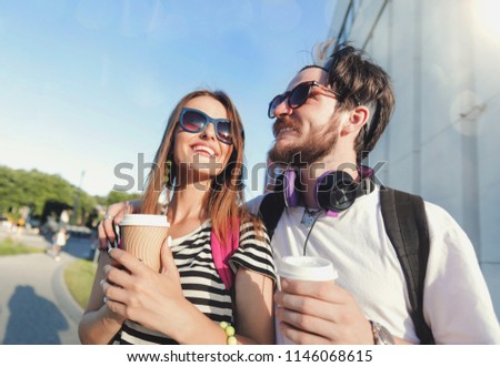 Cute best friends walking at the sunset on the street and drinking coffee, they speaking and listening music