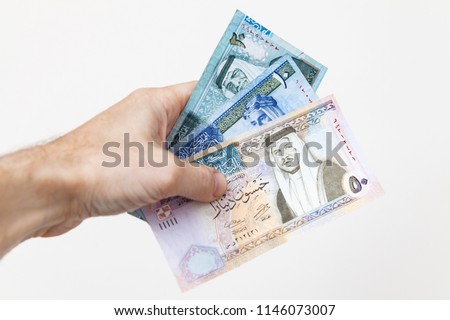 Male hand holding Jordanian dinars banknotes over white wall background, close-up photo Royalty-Free Stock Photo #1146073007