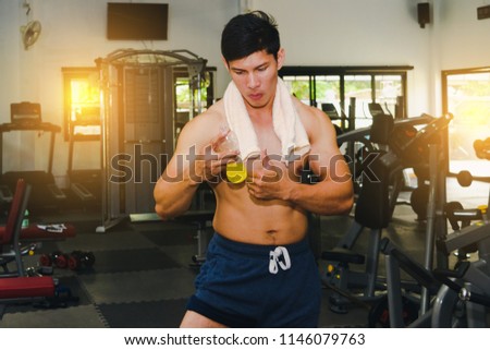 Asian man has muscle exercise in the gym.And Asian handsome muscles are tired, so drink Electrolyte drink.Exercise in gym concept.
