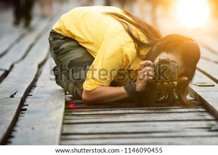 woman photographer taking pictures, shooting from low angle, kneeling  on ground 