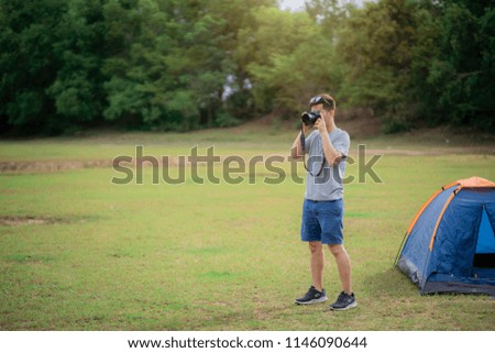 A man holding camera shoot pictures in forest and camping