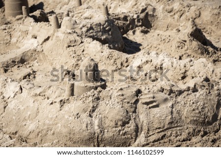Close up on a crumbling sand castle on a sandy beach, with space for text on right