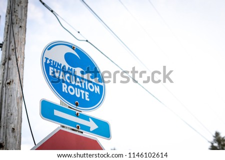 Tsunami Evacuation Route sign with tidal wave icon and arrow, in a residential neighborhood, with space for text on the right