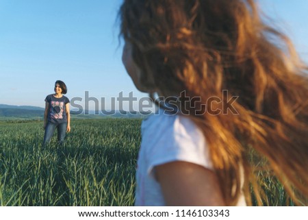 daughter looking at smiling mother in green field