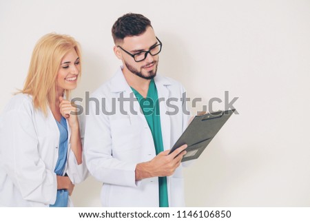 GP doctor looks at data in documents on clipboard while discussing with surgical doctor on white background. Medical service and healthcare concept.
