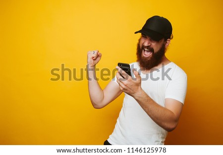 Happy bearded man celebrate success and looking at phone Royalty-Free Stock Photo #1146125978