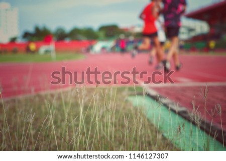Vintage picture of weed and grass field with blurred crowded of runners in background. Exercise and recreation activity in the afternoon. Healthy and wellness concept.