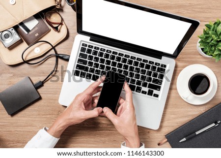 Man hand holding smart phone and using mock up laptop computer