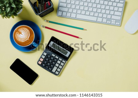Yellow minimal desk with laptop,smart phone,mouse,calculator and cup of coffee.Top view with copy space.