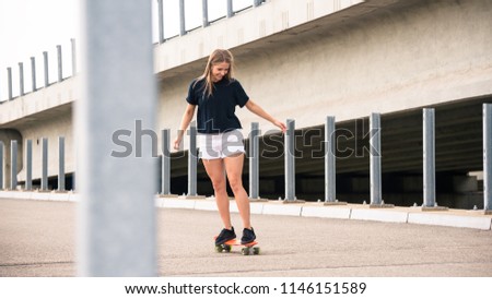 Young Beautiful Blonde Girl Riding Orange Skateboard on the Bridge