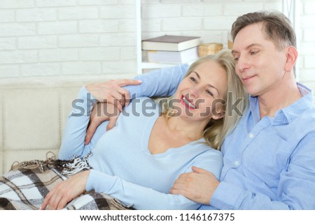 Middle aged couple relaxing on the couch, in a good mood communicate at home in the living room