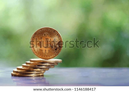 close up stack of gold bitcoin on table, green nature copy space background for text, saving money for future, ethereum cryptocurrency, blockchain business technology concept