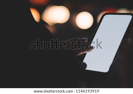 Cropped view of woman's hands holding modern smartphone device with copy space area for your internet advertisement or website.Digital telephone with mock up area on bokeh background