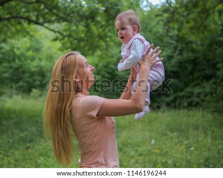 Young mother playing with baby girl outdoor in summer day