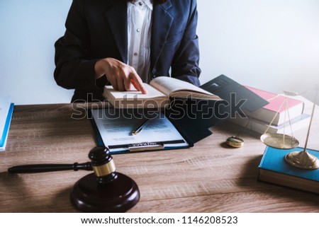 Lawyer woman sitting working with reading law book and wooden gavel on table in office. justice and law ,attorney, court judge, concept.