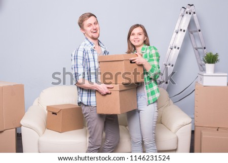 Family, new apartment, emotions and moving concept - couple of young happy people stack their box together because of moving in new apartment and smile