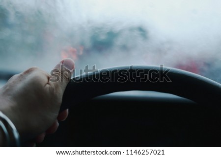 man driving car, hand on steering wheel, looking at the road ahead, selective focus on hand with shallow depth of field.  (Security Equipment concept)