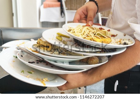 A lot of dirty plates with scraps in the hands of the staff Royalty-Free Stock Photo #1146272207