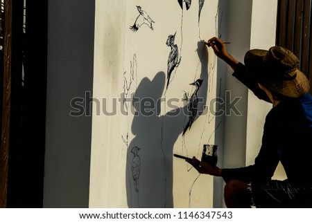 Man painting art drawings on the front door of the house is a woodpecker.