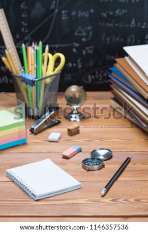 School books and stationery on a wood and a chalkboard background written with mathematical formulas and equations