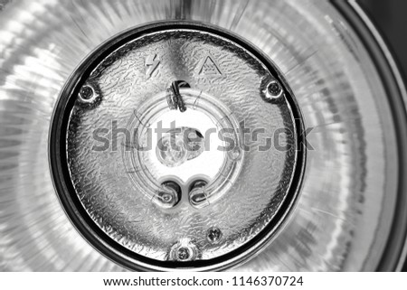 Reflector, pilot light bulb and round flash bulb of an studio flash head close-up. Monochrome image