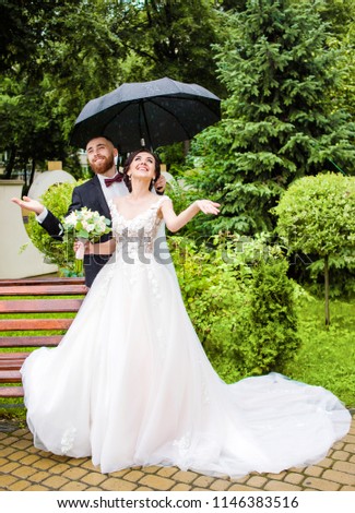 The emotional lovely of a couple standing on the nature in the rainy weather under the umbrella