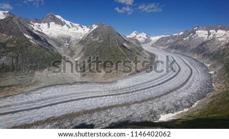 Scenic aerial overlook on Aletsch Glacier from UNESCO Ridge Trail with its specific bend and dominated by majestic Alpine Peaks such as Jungfrau or Aletschhorn - Glorious Summer hike in Switzerland