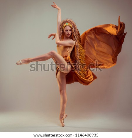 Ballerina with indian feathers. Young graceful woman ballet dancer, dressed in professional outfit, shoes and white weightless skirt is demonstrating dancing skill. Beauty of classic ballet.
