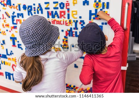 Close-up details of children playing along the wall full of names made from colorful puzzle blocks. Colorful abstract puzzle, letter details and textures.