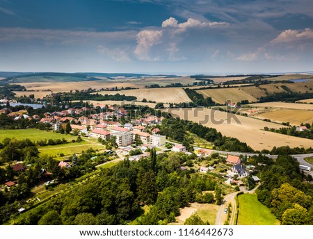 Drone flying above the trees and little town. Blue dramatic sky with green trees with little buildings. shot above the ground in South Moravia Czech Republic