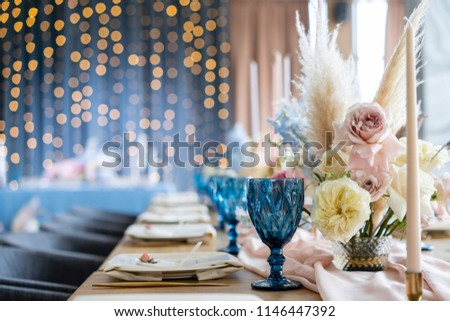 Wedding Banquet or gala dinner. The chairs and table for guests, served with cutlery and crockery. Covered with a pastel pink tablecloth runner. party lighted with garlands Royalty-Free Stock Photo #1146447392