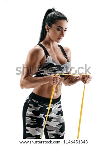 Beautiful strong model performs exercises using a resistance band. Photo of latin woman in military sportswear isolated on white background. Strength and motivation