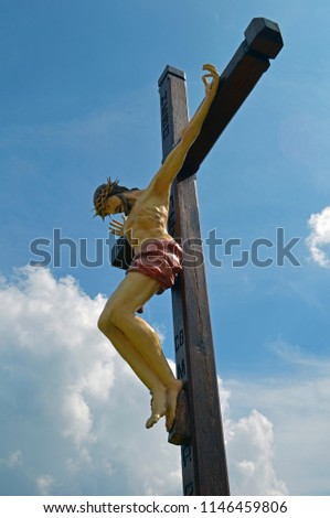 Jesus Christ crucified on a cross on the background of a blue sky with clouds