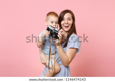 Portrait of happy family. Mother keep in arms, have fun, hug son baby boy, take picture on retro vintage photo camera on pink background. Sincere emotions, Mother's Day, parenthood, childhood concept