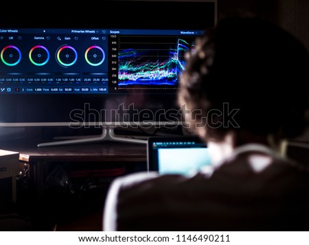 back view of young man in the dark studio color grading video with laptop and external monitor Royalty-Free Stock Photo #1146490211