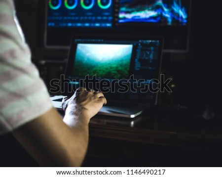 young man edit video in dark studio using color grading tools and modern equipment Royalty-Free Stock Photo #1146490217
