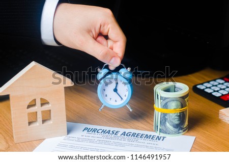 The hand of a businessman keeps an alarm clock on the contract for the purchase of property or real estate. Little time, limited. Long-term lease of property. Concept of the contract purchase and sale Royalty-Free Stock Photo #1146491957