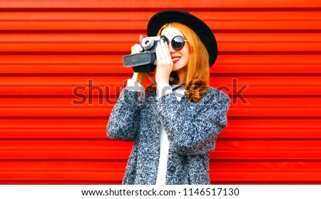 Happy pretty woman holds retro camera on a red background