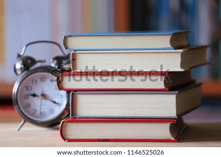 Close-up of books stacked on library table alarm clock next to book row is the background selective focus and shallow depth of field