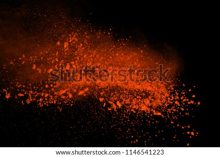 Orange powder explosion isolated on black background. Freeze motion of colored dust splatted.