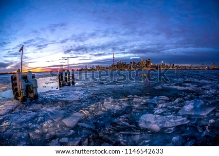 Frozen lake at late sunset onlooking Toronto skyline from the Ward's Island ferry dock.